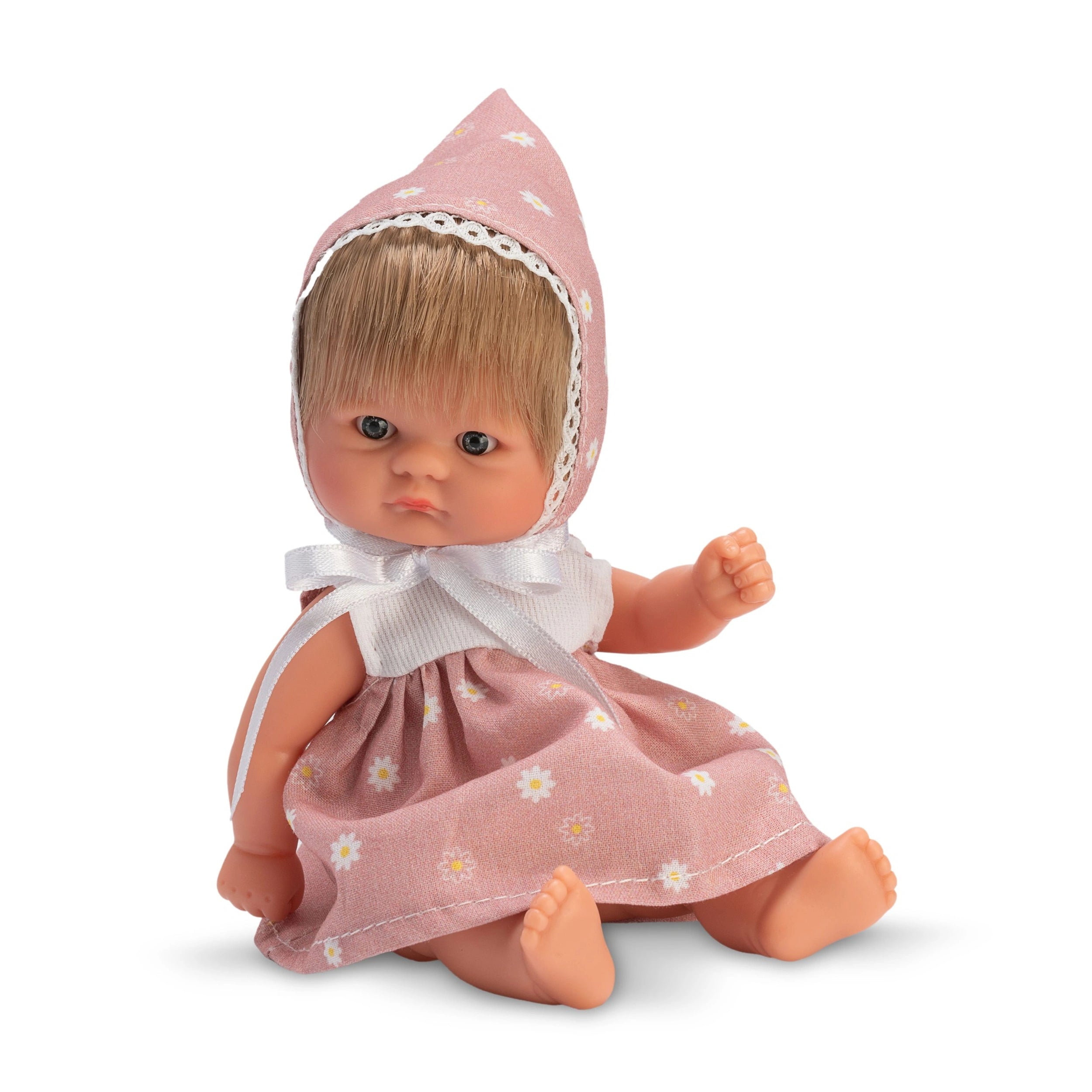 Bonboncin doll wearing a pink floral dress and bonnet, seated with a neutral expression, soft rubber body visible.