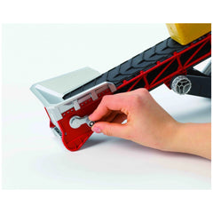 Hand turning crank on red and black Bruder Conveyor Belt toy with hay bale.