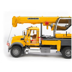 Yellow Bruder MACK Granite Liebherr crane truck with extendable boom, detailed cabin, and adjustable support legs on display.