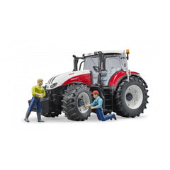Toy tractor Bruder Steyr 6300 Terrus CVT with two figurines, one standing and one kneeling, beside large wheels.