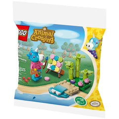Colorful Lego set featuring Julian from Animal Crossing painting on a beach, surrounded by green plants and a sandy shore.