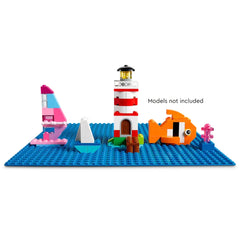 A vibrant blue LEGO® Classic baseplate features a red and white lighthouse, colorful sailboats, an orange fish, and coral.
