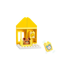 Bright yellow DUPLO house with a bear figure in a crib and a clock block alongside, featuring a playful design to represent daily routines.