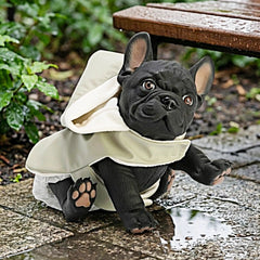 ASI Dolls - Nono The Bulldog in a green raincoat, sitting on a wet surface with a playful expression, set in a garden.