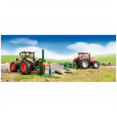 Toy forestry set with two tractors, figures using log splitters and tools, on a grassy, rocky landscape under a blue sky.