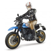 Rider on blue Bruder Scrambler Ducati Desert Sled toy bike with detailed features and studded tires.