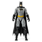Batman Rebirth action figure stands in a dynamic pose, showcasing its black and gray design with a glossy cape and cowl.