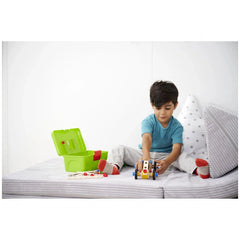 Eichhorn Constructor Racer Car toy is being played with by a child in a blue shirt, sitting on a bed with white and gray bedd