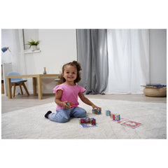 Eichhorn Picture Cube Friends set with colorful puzzles, girl smiling while holding the box on a cozy, modern rug.