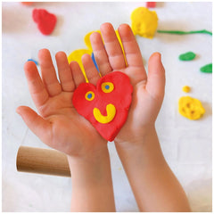 Feuchtmann My Favorite Clay pack with a child’s hands holding a red heart-shaped clay object on a textured white surface.