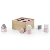 Label-Label-Shape-Sorting-Box features a wooden box with a pink lid and gray, white, and pink cubes arranged on the right.