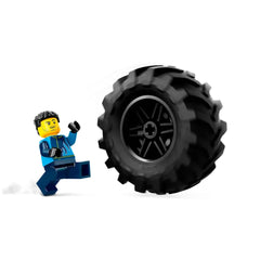 LEGO® City minifigure in a blue outfit, excitedly running towards a large black monster truck tire, showcasing outdoor adventure fun.