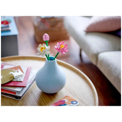 Colorful LEGO® Creator Lotus Flowers in a light blue vase, featuring pink and white blooms with green stems, placed on a wooden table.