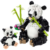 A detailed LEGO Panda Family set featuring a large adult panda and a smaller baby panda, both made of black and white bricks. The adult panda holds a bamboo stalk, while the baby panda plays with a small green piece. In the background, green bamboo shoots and a colorful flower arrangement enhance the scene, creating an engaging and vibrant playset designed for imaginative storytelling.