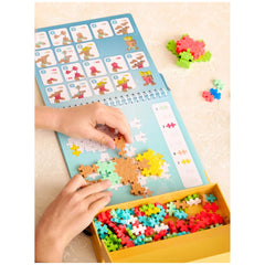 Plus Plus Ocean Activity Pad with blue cover, puzzle pieces in yellow container, and a hand holding a colorful piece.