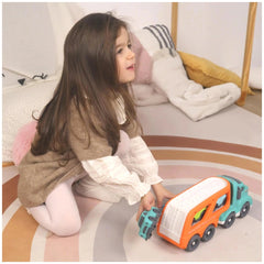 Baby Challenge Sustainable Car Transporter Set is being played with by a young girl on a colorful patterned floor.