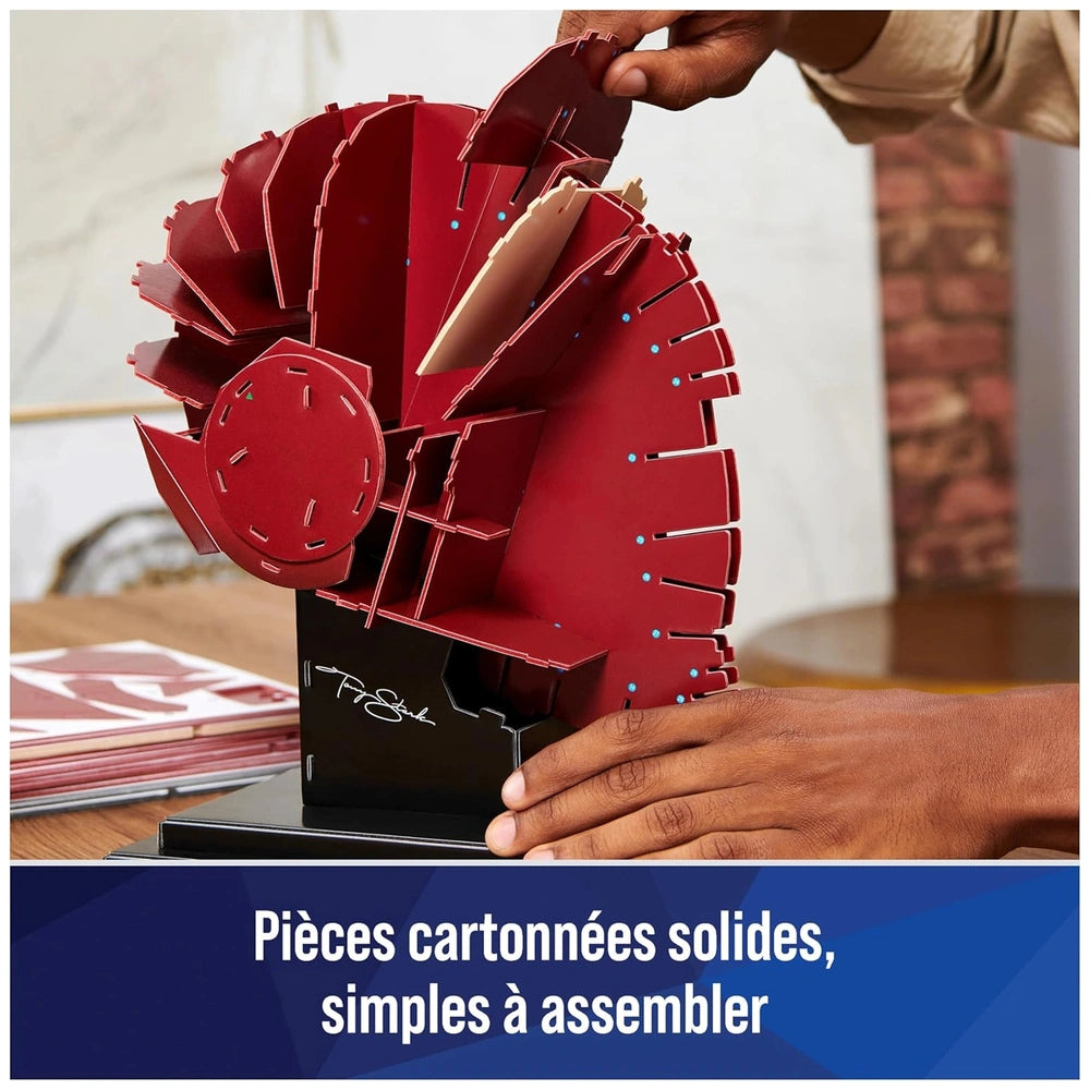 Red 3D Iron Man puzzle model held in hand, featuring intricate designs and a glossy finish against a blurred indoor backgroun