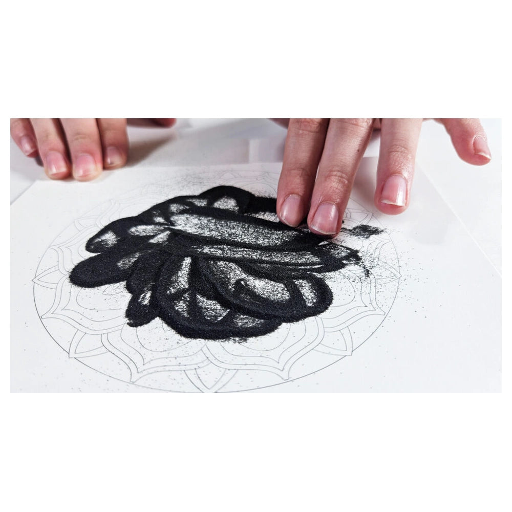 Sand Art Mandala activity features hands applying black substance on white paper, showcasing creativity and eco-friendly craf