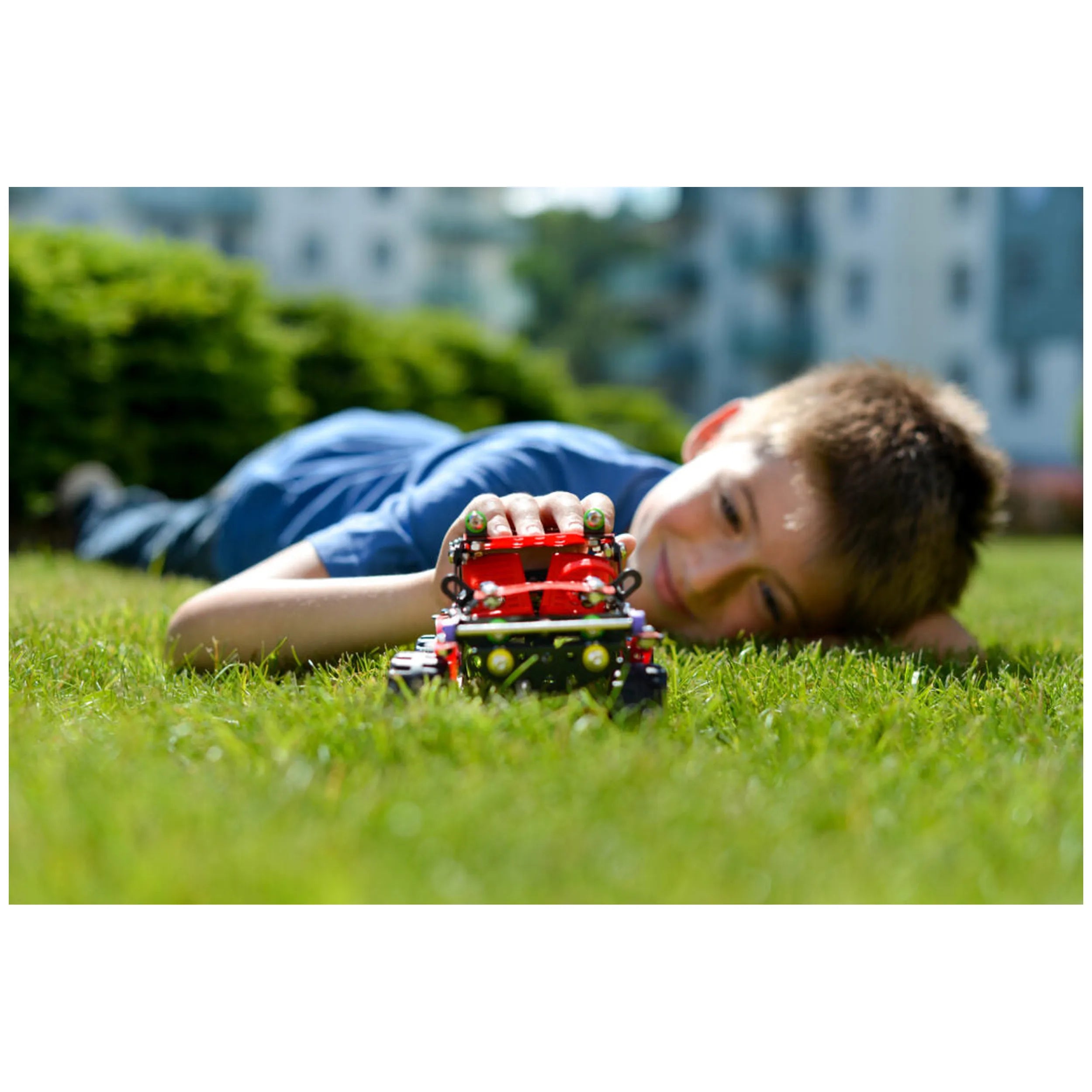 Child playing with Alexander Constructor Off-Road Machine Black Spider in the grass on a sunny day.