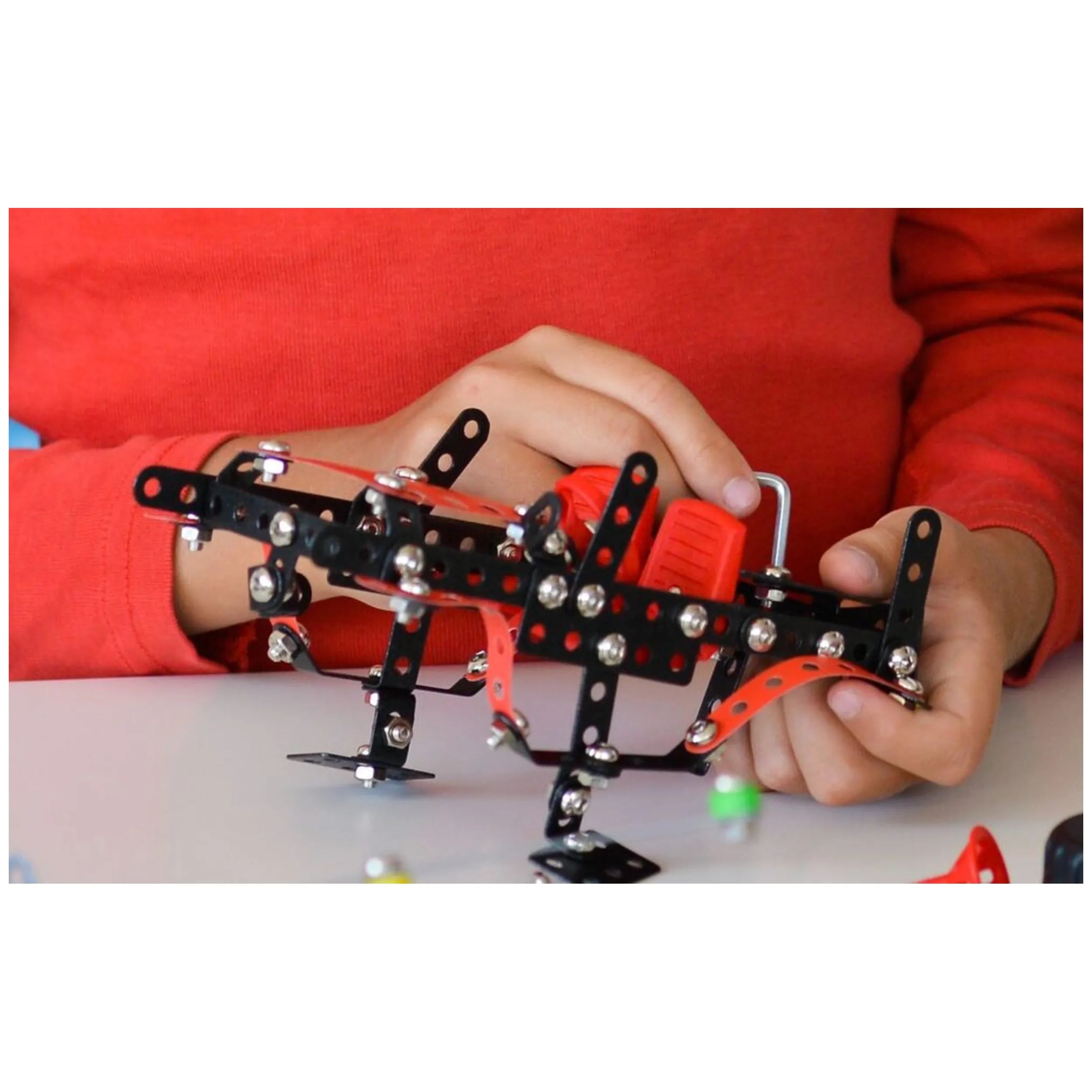 Child assembling Alexander Constructor Off-Road Machine with black and red metal pieces, enhancing creativity and manual skills.
