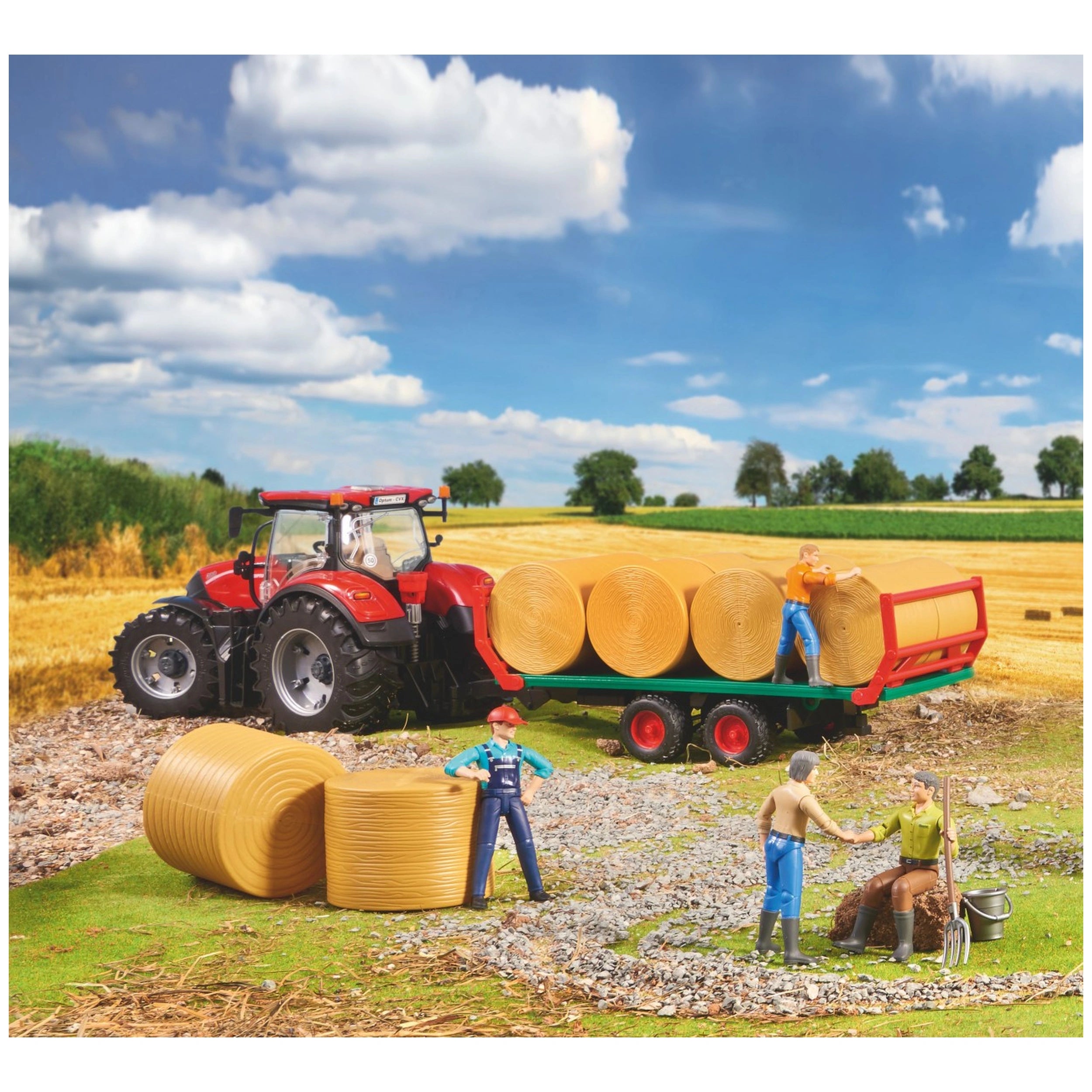 Toy red tractor with bale transport trailer, carrying yellow round bales on a farm. Miniature figures in work scene.