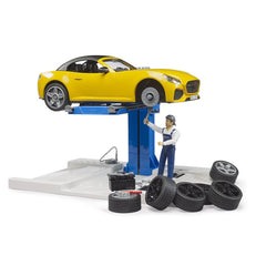 Yellow toy roadster on lift at car service center with mechanic figure and tires around.