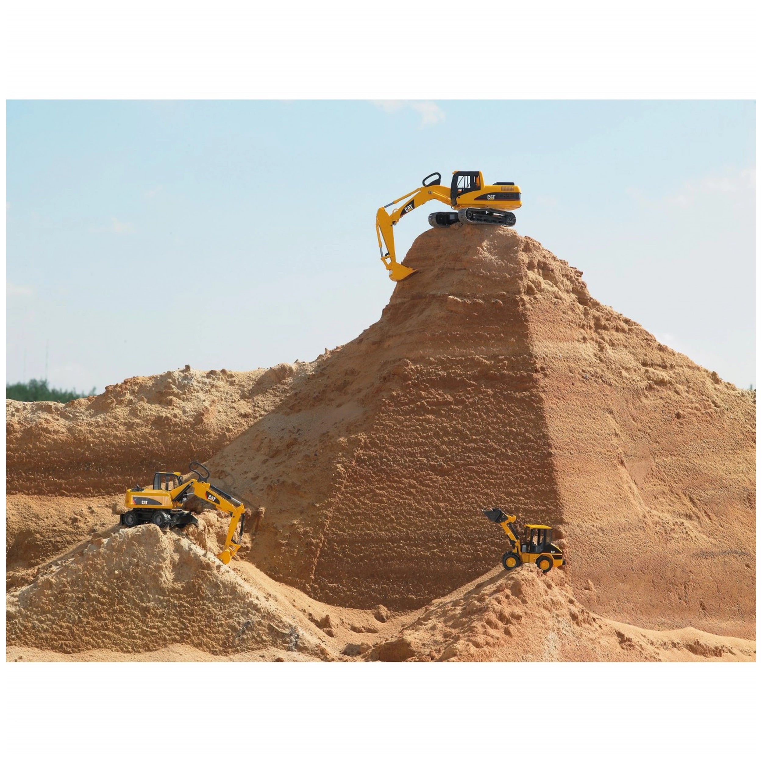 Yellow Bruder CAT® Wheel Excavators on sand dunes, showcasing realistic design in a construction play scene.