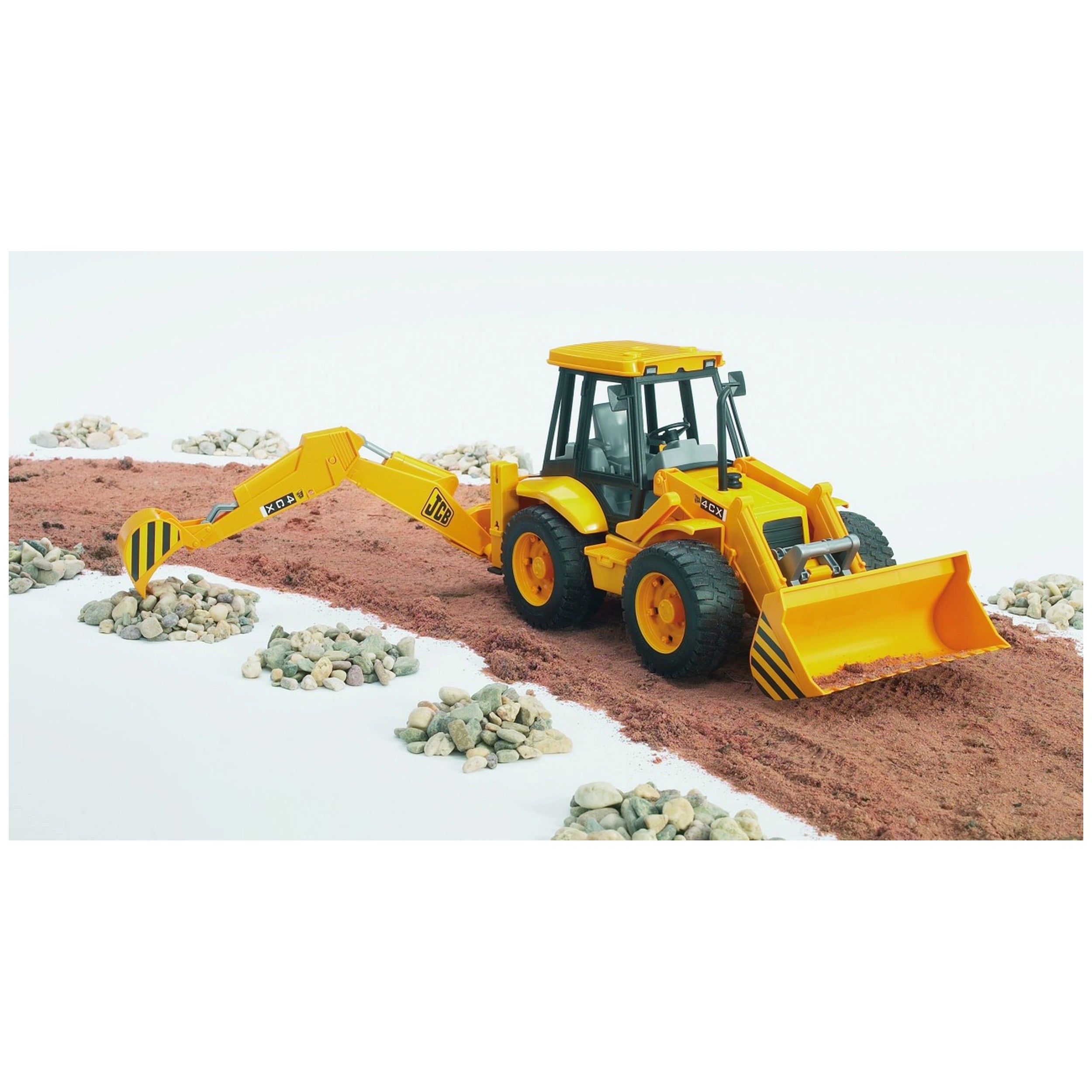 Yellow Bruder JCB 4CX Backhoe Loader toy on dirt path, surrounded by small rocks, features movable arm and front loader.