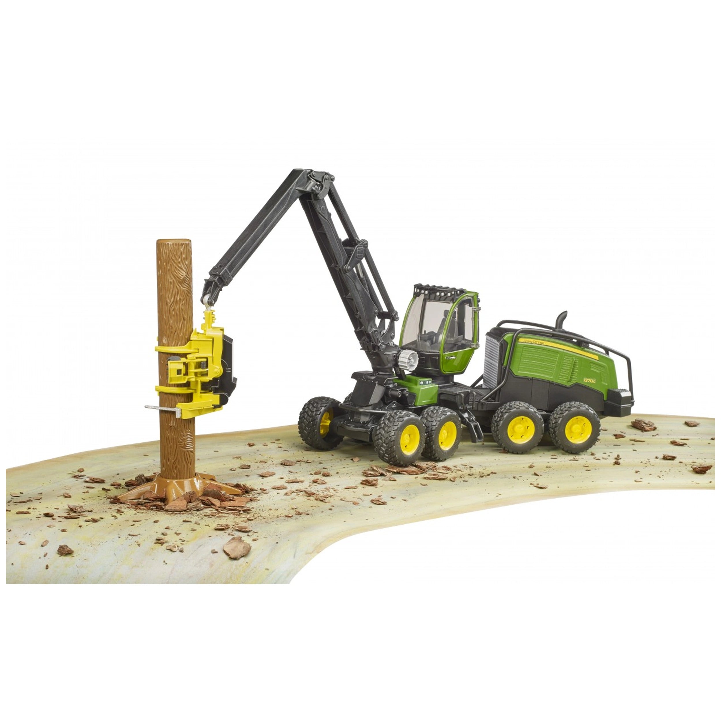 John Deere 1270G Harvester toy on an earth-like surface, gripping a tree trunk with yellow machinery arm.