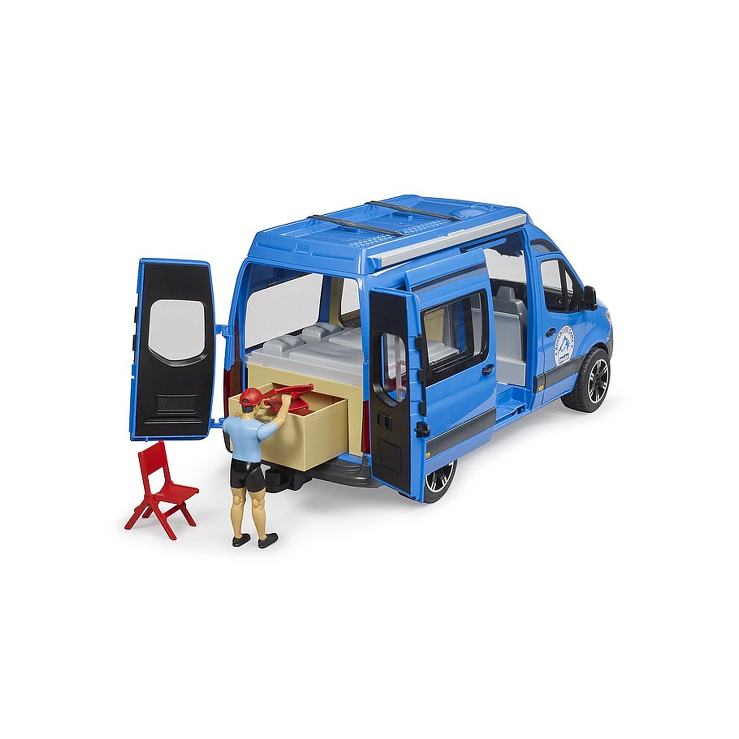 Blue toy camper van with open doors, revealing interior bed. A figure in red cap arranges items. Red chair nearby.