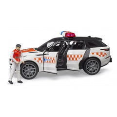 White and orange Bruder Range Rover Velar toy ambulance with driver figure, doors open, featuring emergency lights.