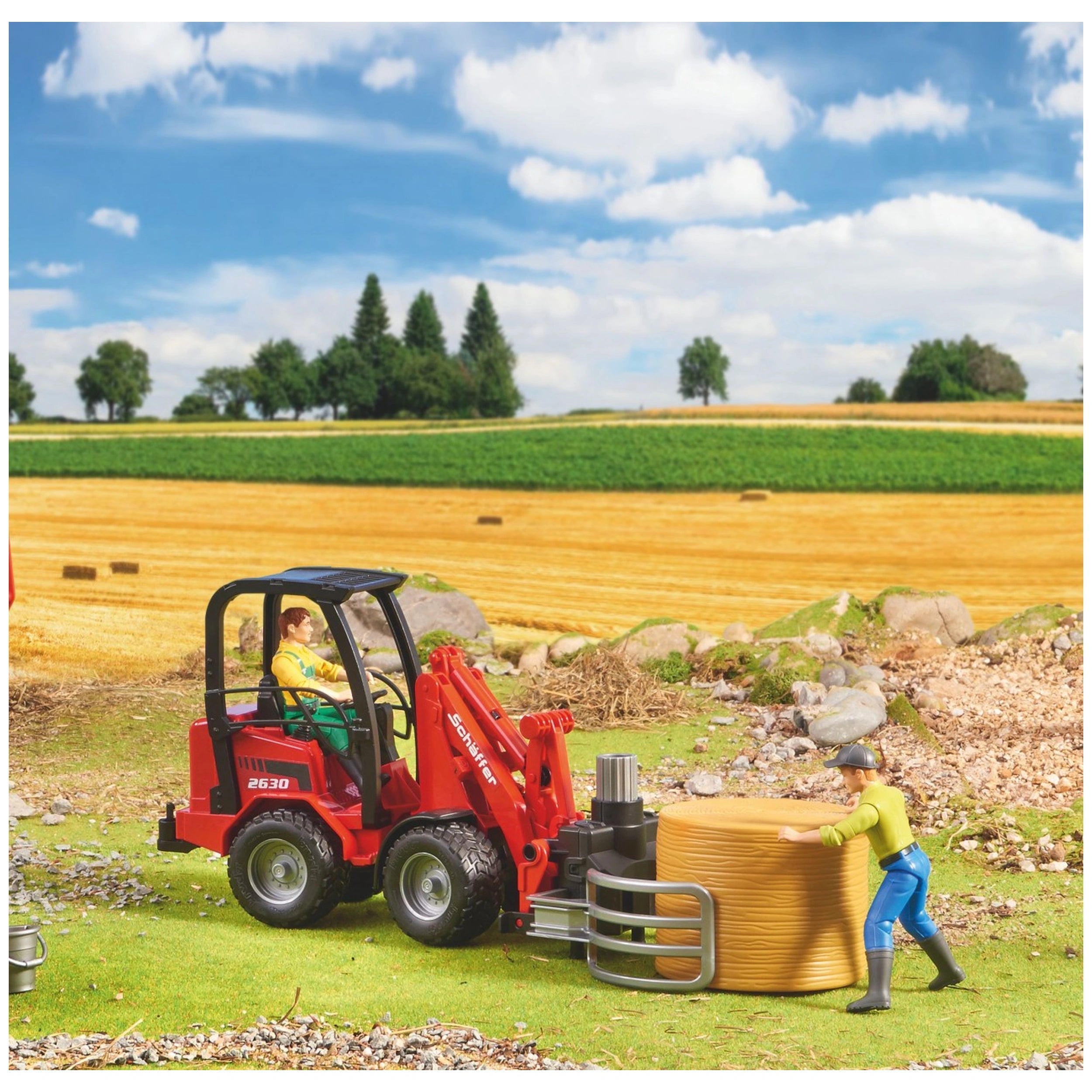 Red Bruder Schäffer Compact Loader 2630 with bale gripper, a toy farmer, and hay bale in a vibrant farm landscape.