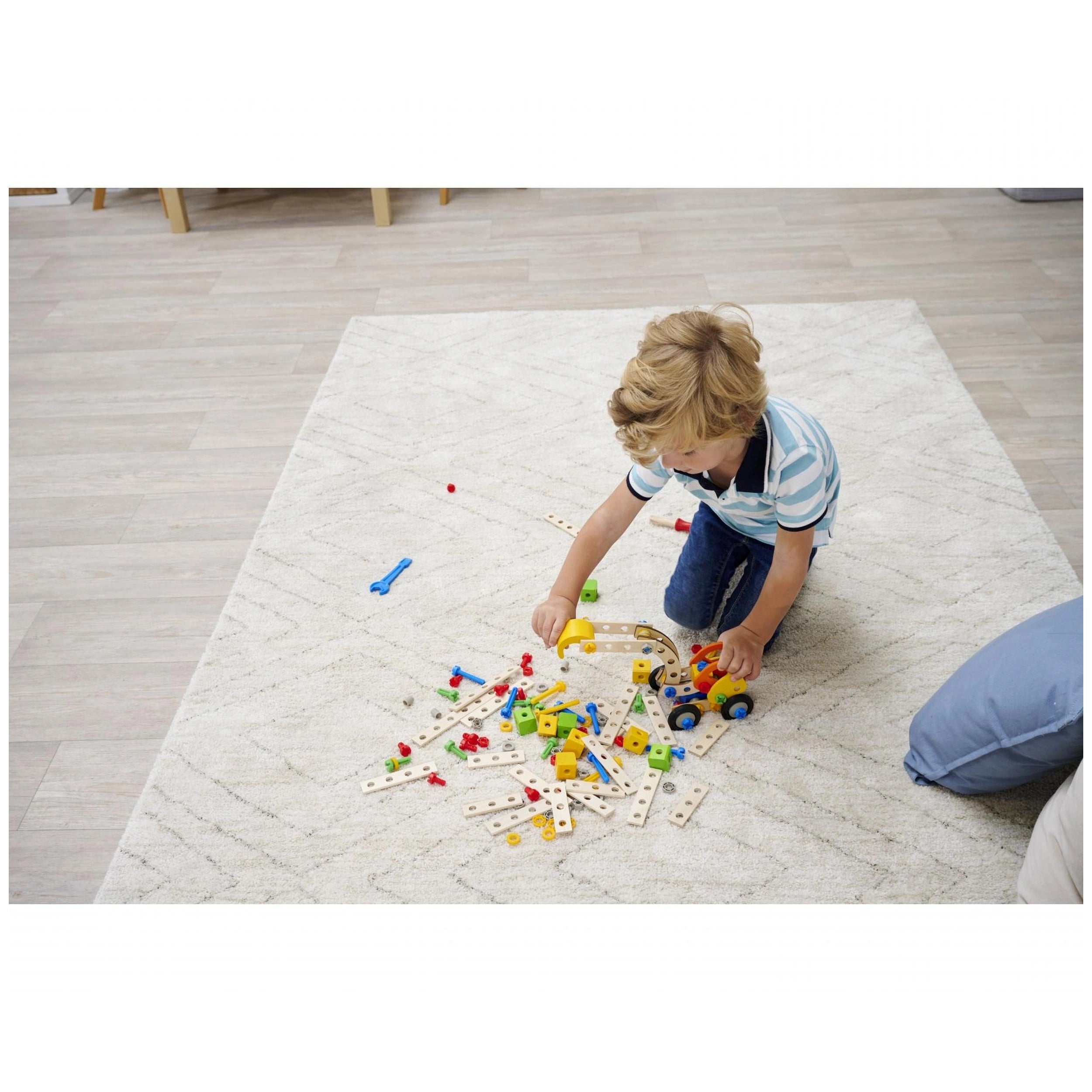 Eichhorn Constructor 3in1 construction set with colorful plastic pieces and a young child playing on a textured rug.