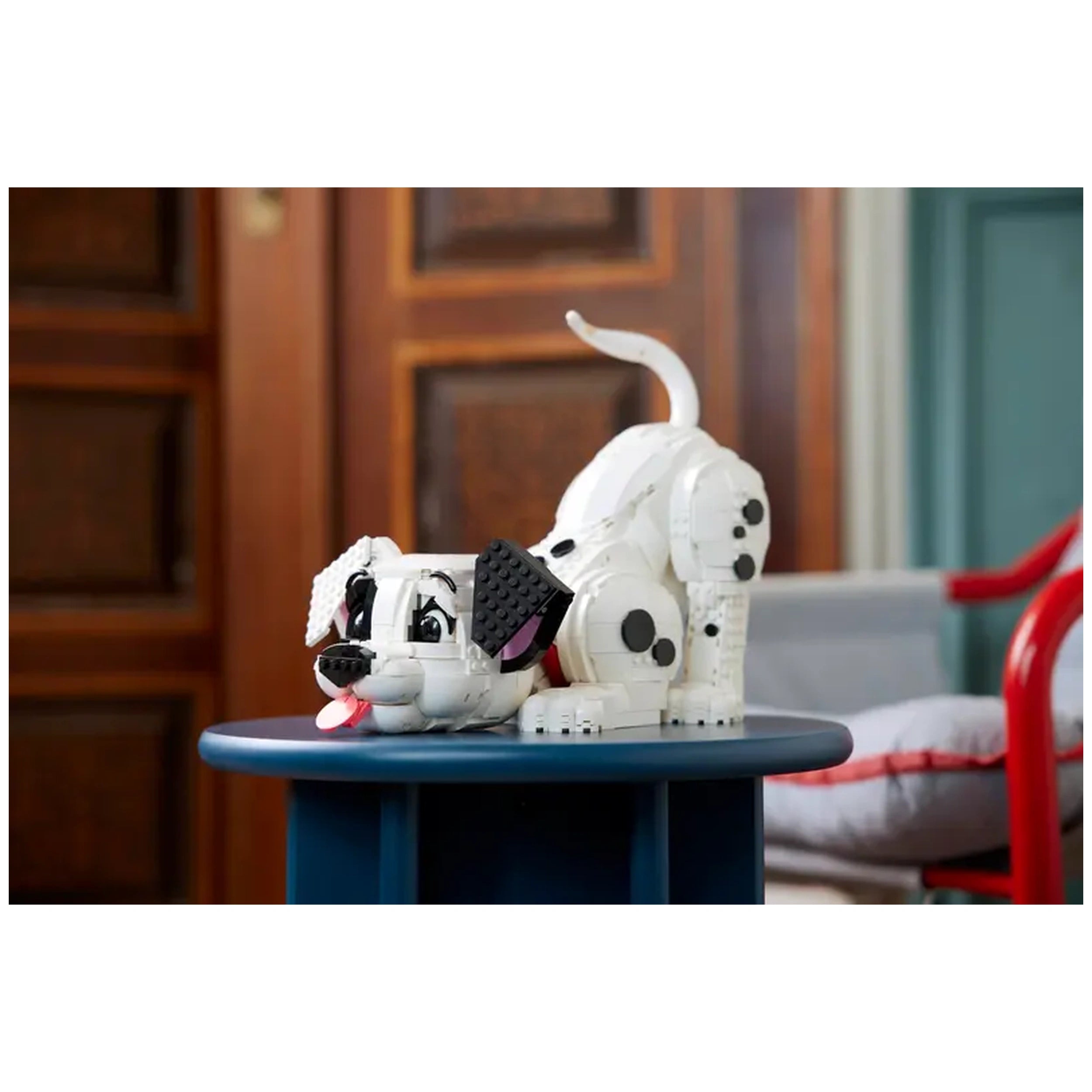 LEGO Dalmatian puppy model resting playfully on a blue table, showcasing black spots, bright eyes, and a playful expression.