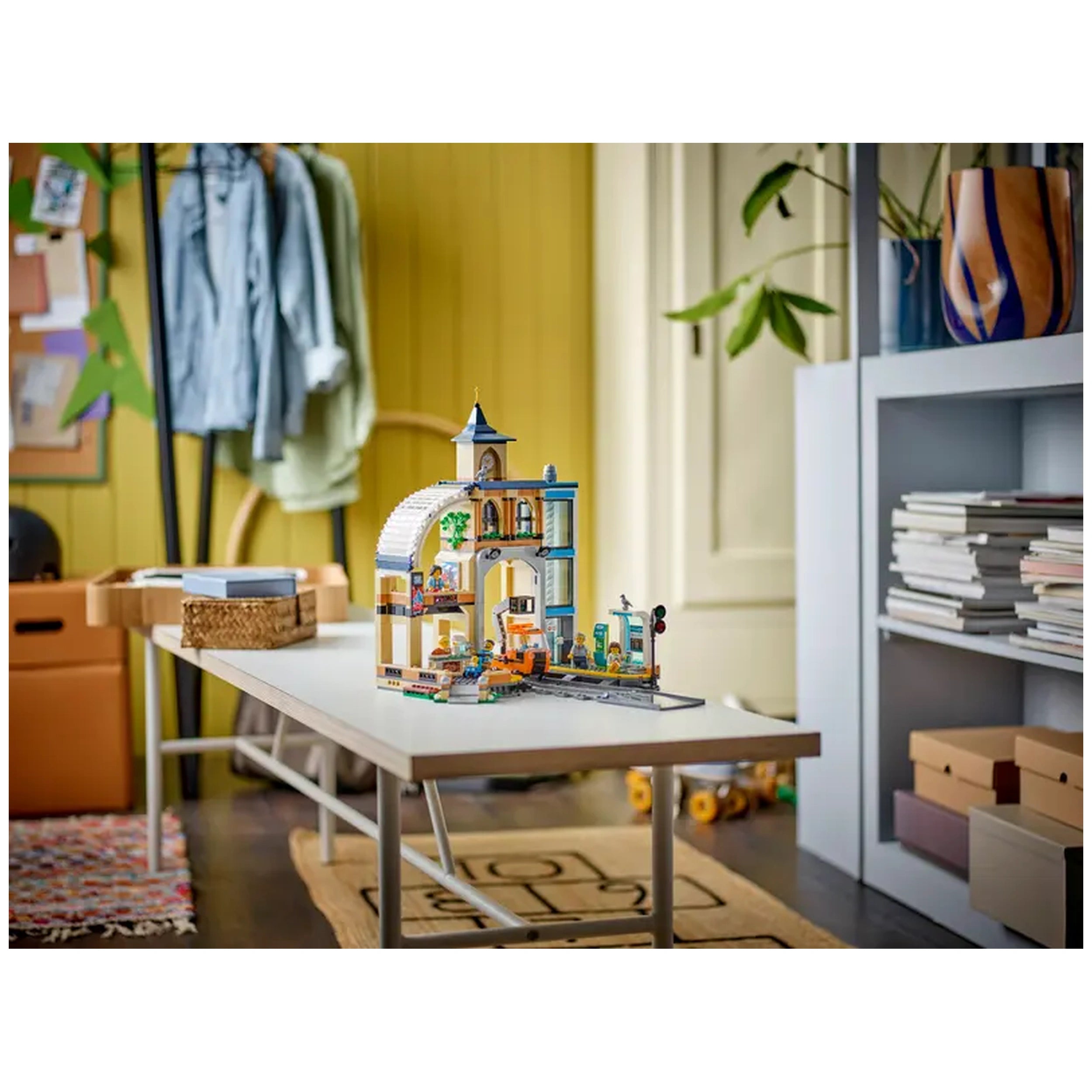 Colorful LEGO Central Train Station construction set displayed on a modern table, surrounded by a cozy room with plants and soft lighting.