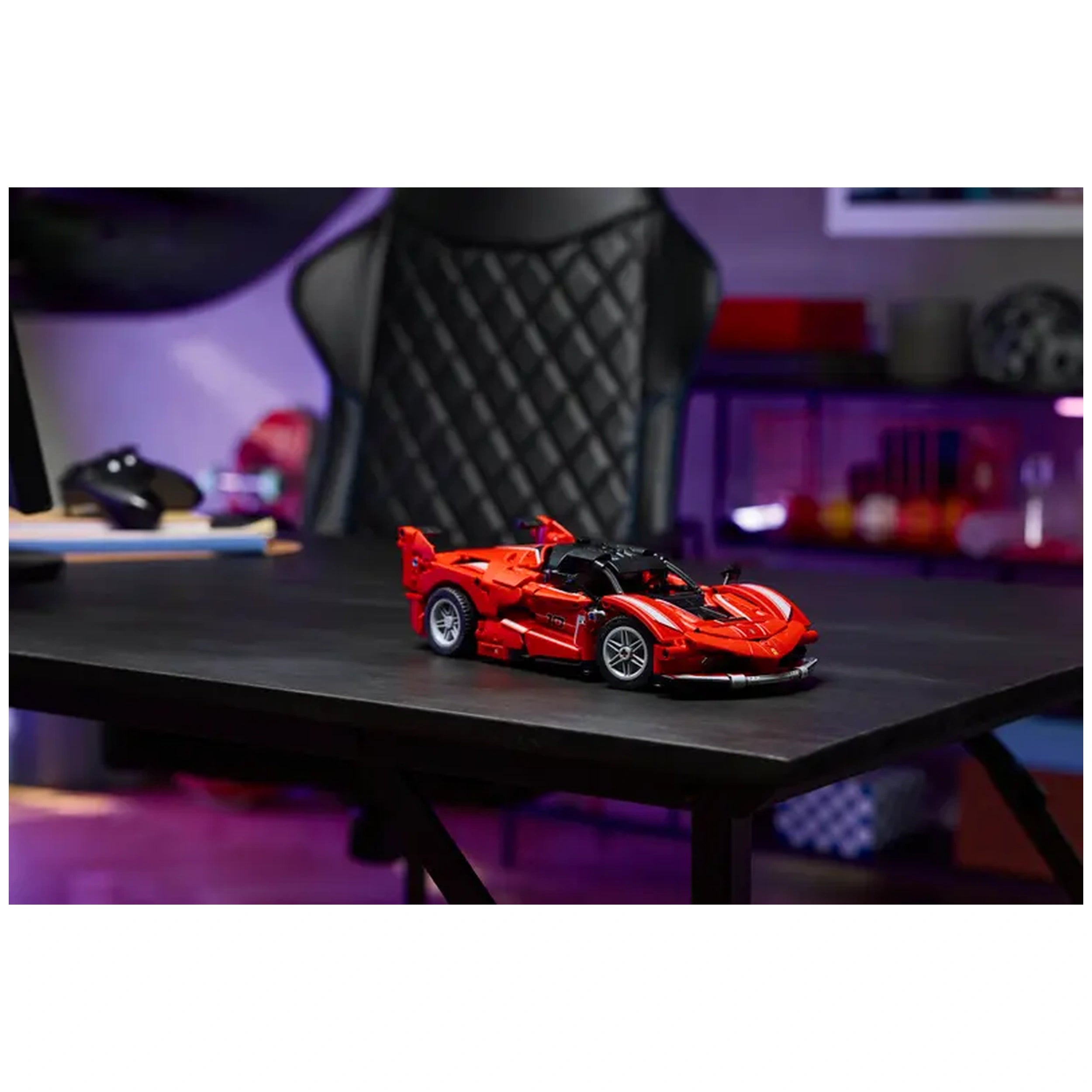 LEGO Ferrari FXX K model car kit in vibrant red, displayed on a sleek black table, with a modern gaming chair in the background.
