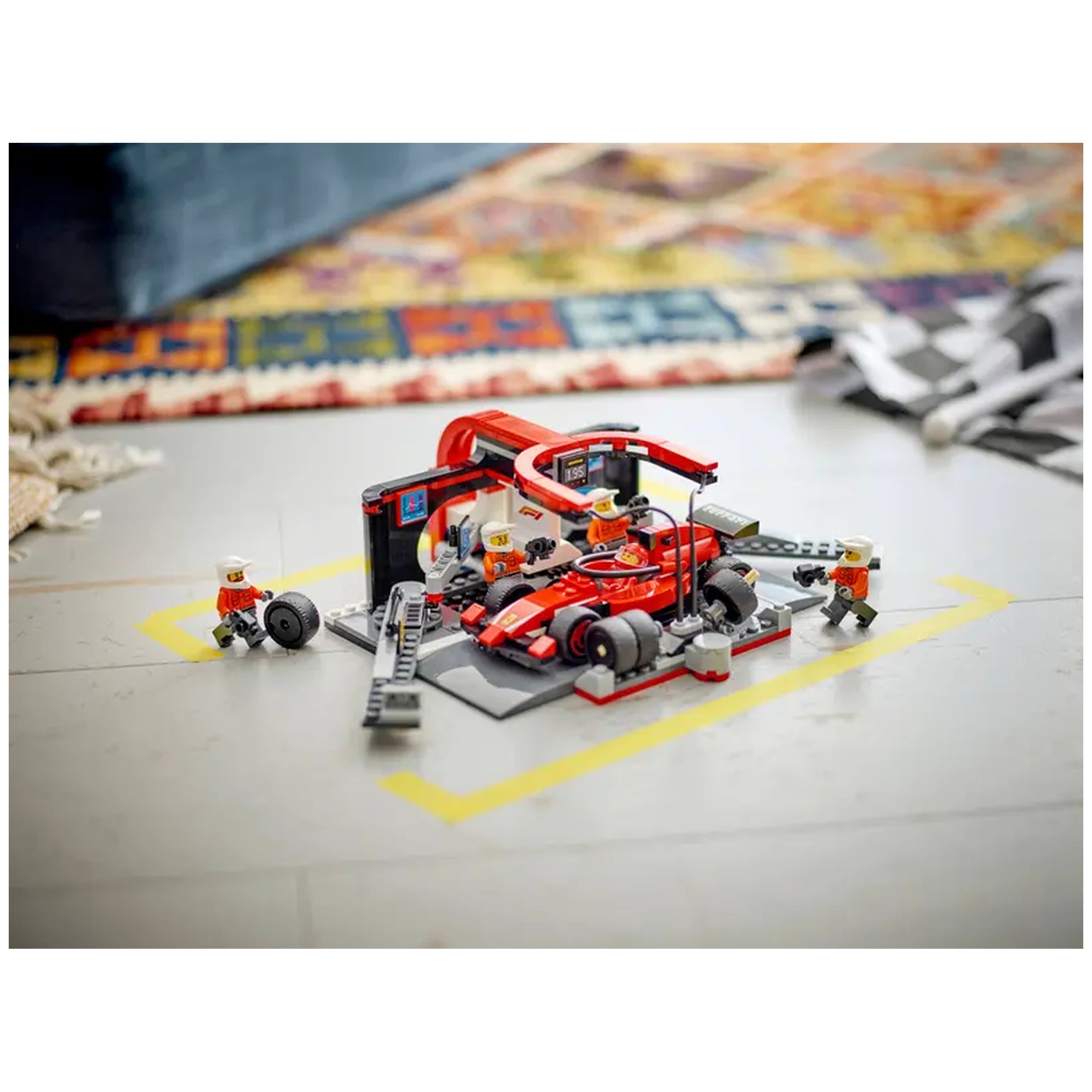 LEGO City F1 Pit Stop set with a red Ferrari car, pit crew minifigures, and accessories on a gray surface, capturing the excitement of racing.