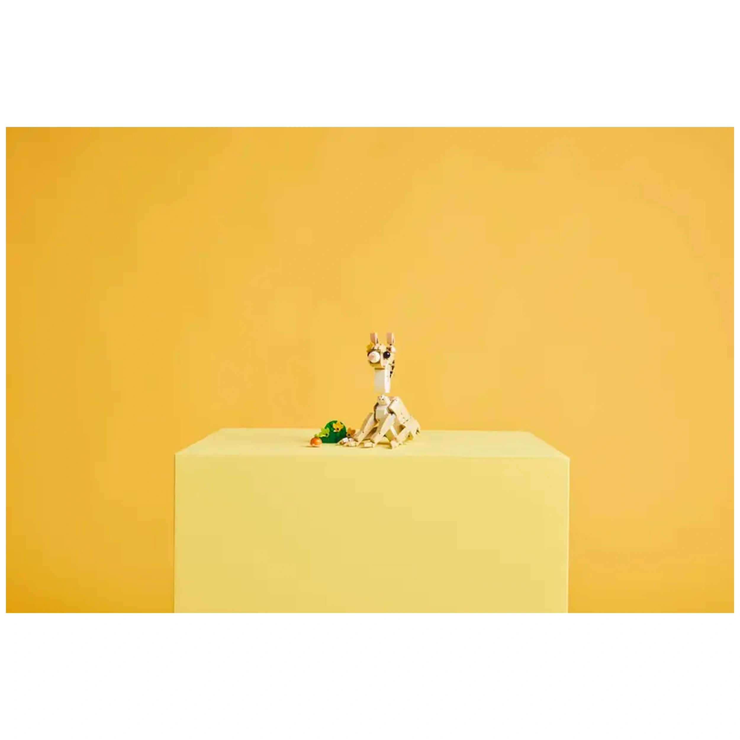 LEGO Creator Cute Bunny construction set displayed on a light yellow pedestal, featuring a posable bunny, a carrot, and a patch of green grass.