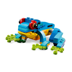 Colorful LEGO frog model showcases vibrant blue, yellow, and green bricks with posable limbs, resting on bright green lily pads.