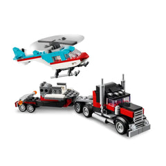Lego Creator Flatbed Truck in red and black, towing a helicopter in blue and red. The helicopter features spinning rotor blades.