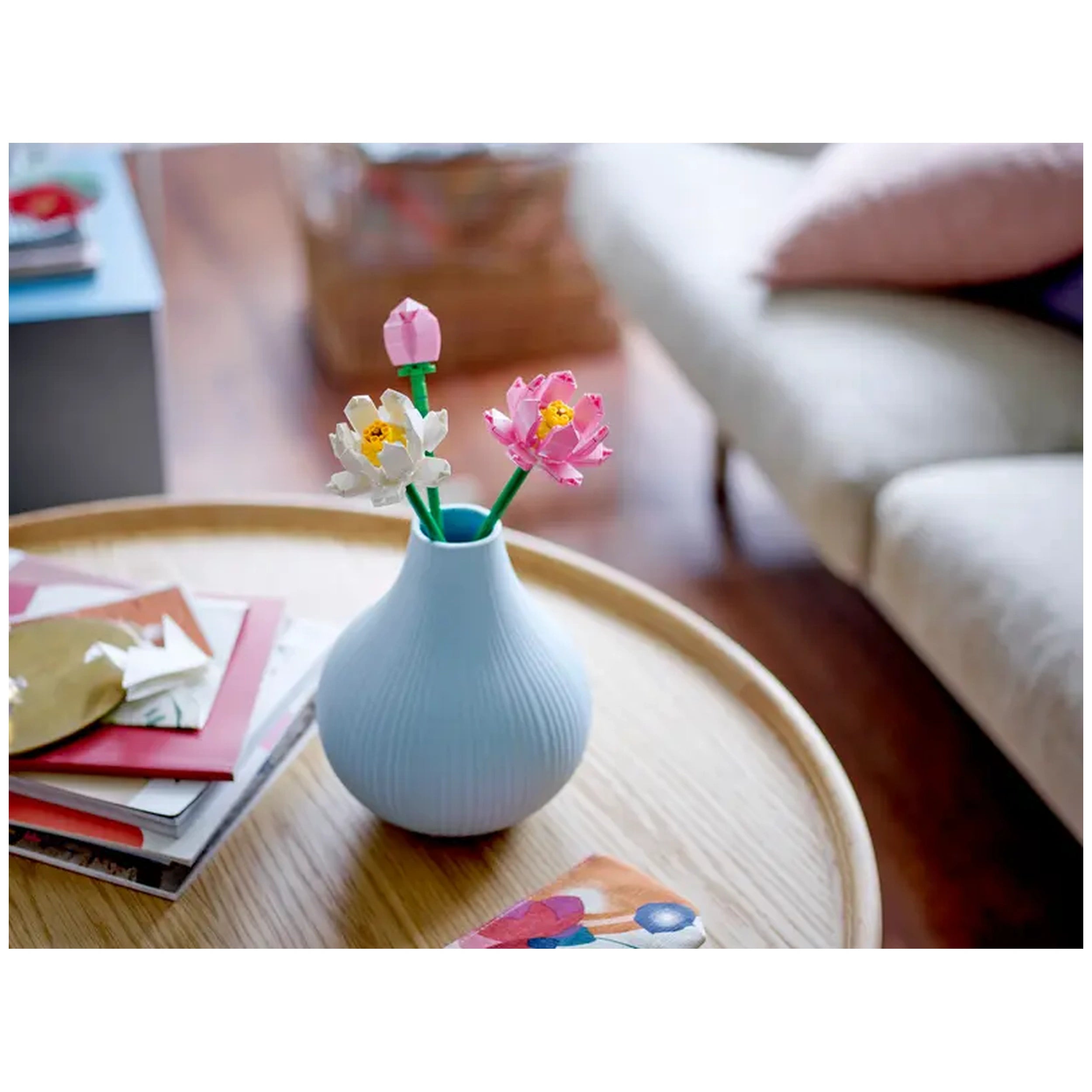 Colorful LEGO® Creator Lotus Flowers in a light blue vase, featuring pink and white blooms with green stems, placed on a wooden table.