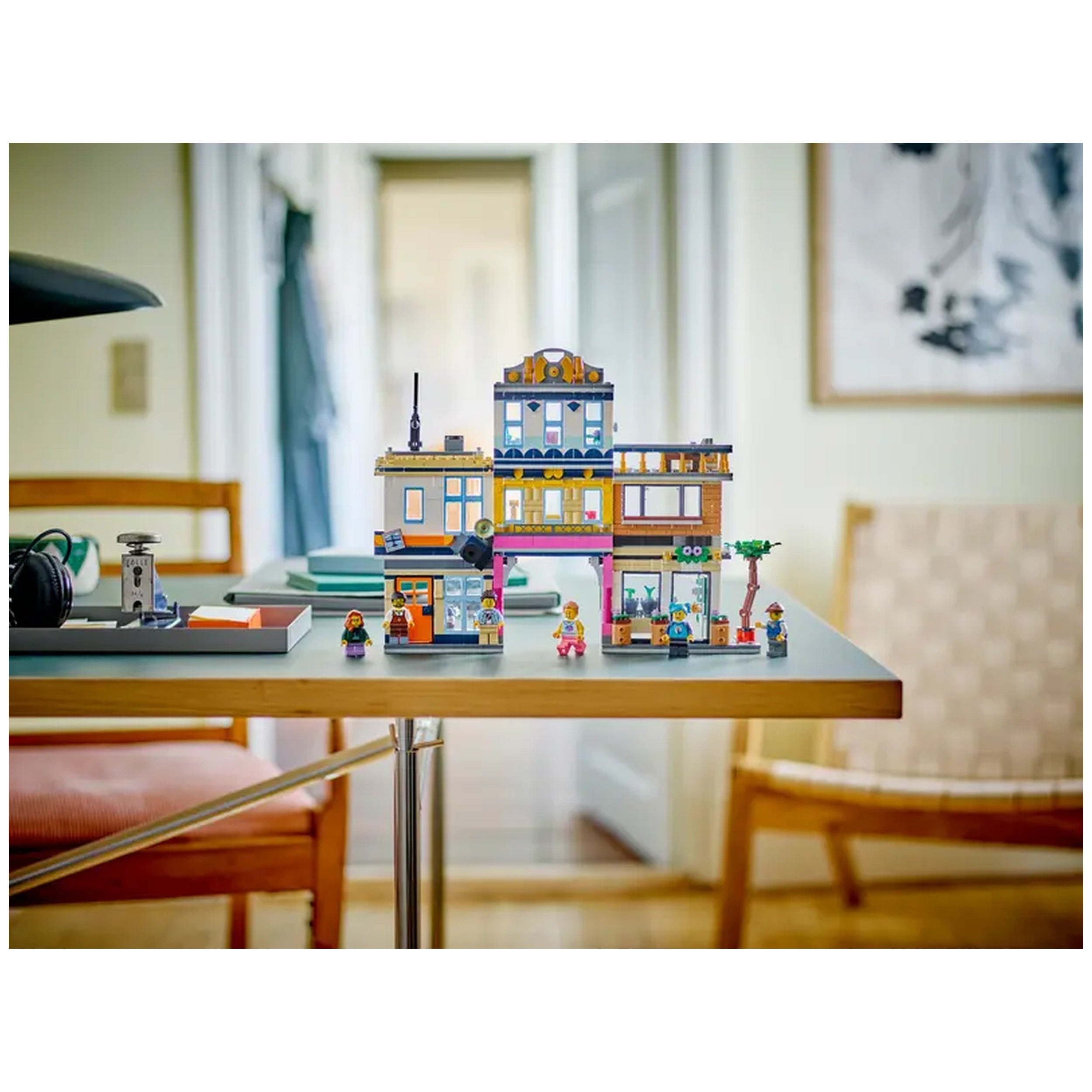 Colorful LEGO® Creator 3in1 Main Street set on a light wooden table, featuring a three-floor hotel, music and record stores, café, and mini figures.