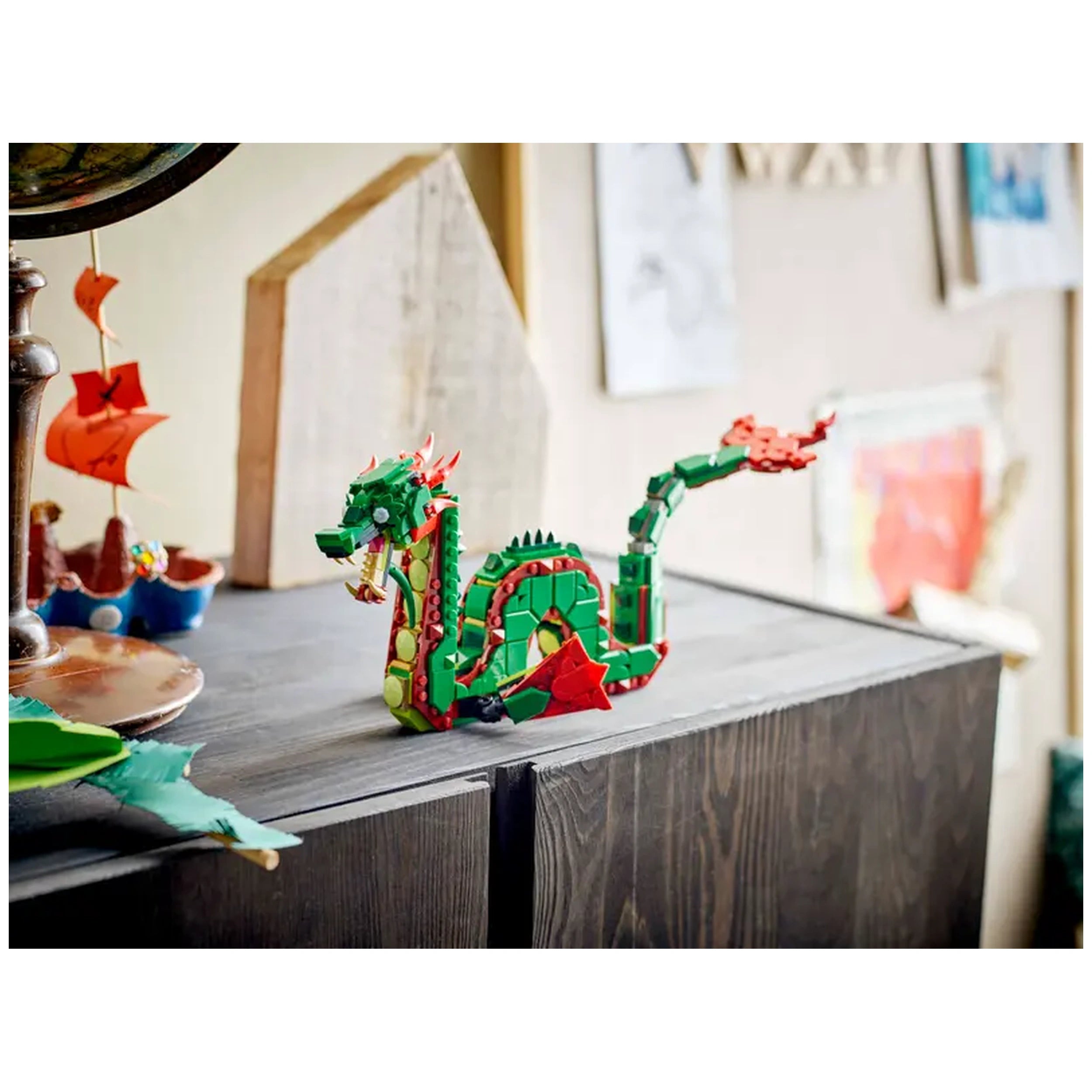 Colorful LEGO® Creator Medieval Dragon set with posable features, displayed on a wooden table alongside a ship and other toys.