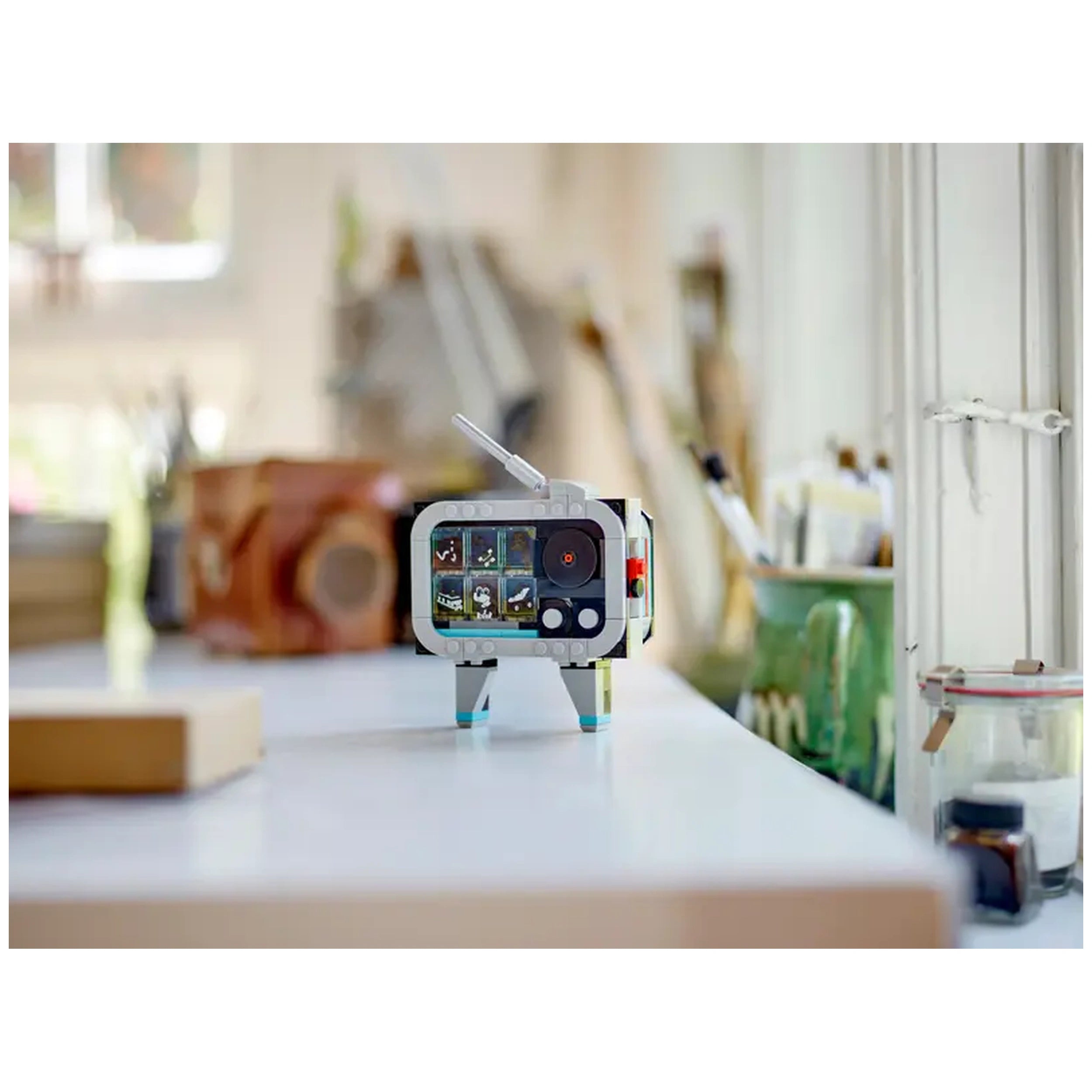 LEGO® Creator Retro Camera construction set, featuring a retro design with vibrant stickers, placed on a table among artistic supplies.