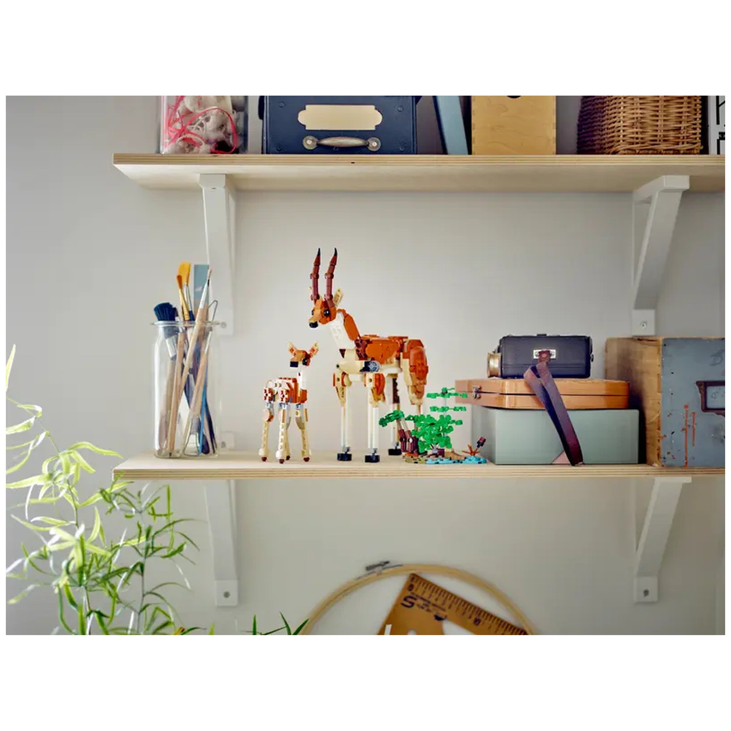Colorful LEGO Creator Wild Safari animal models, including a giraffe and a smaller animal, displayed on a wooden shelf with art supplies.