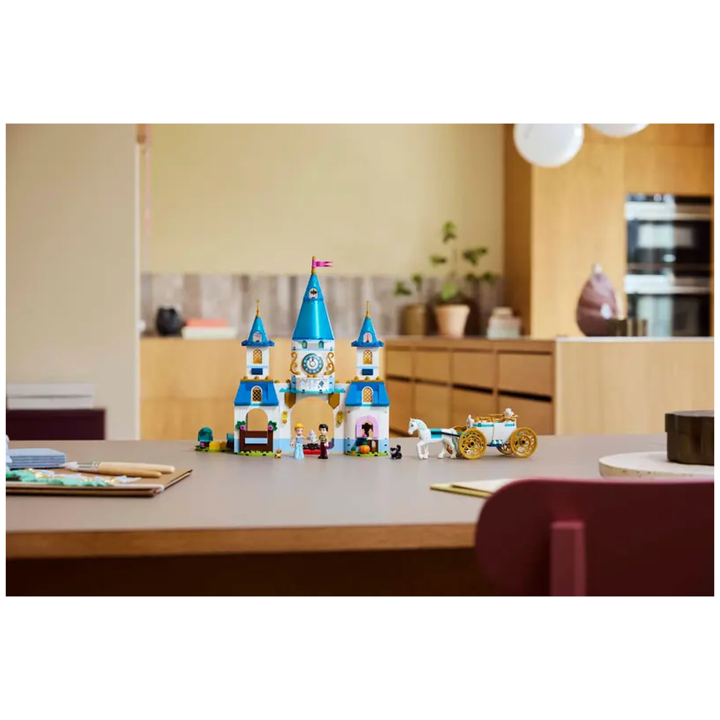 A colorful LEGO® Disney Princess Cinderella’s Castle set featuring a blue tower, a horse-drawn carriage, and mini-figures of Cinderella and friends on a wooden table.