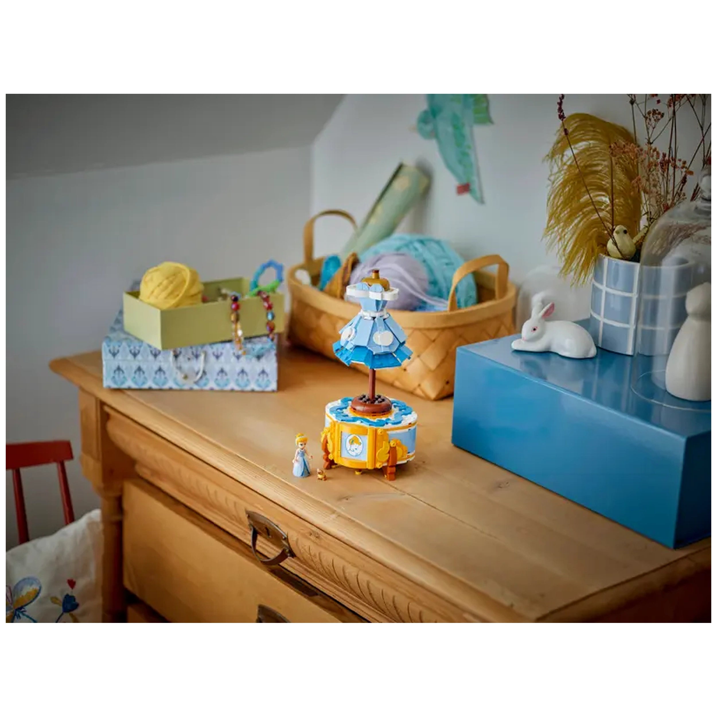 LEGO Cinderella's Dress set displayed on a wooden table, with a minidoll of Cinderella, decorative boxes, and a bunny figurine nearby.