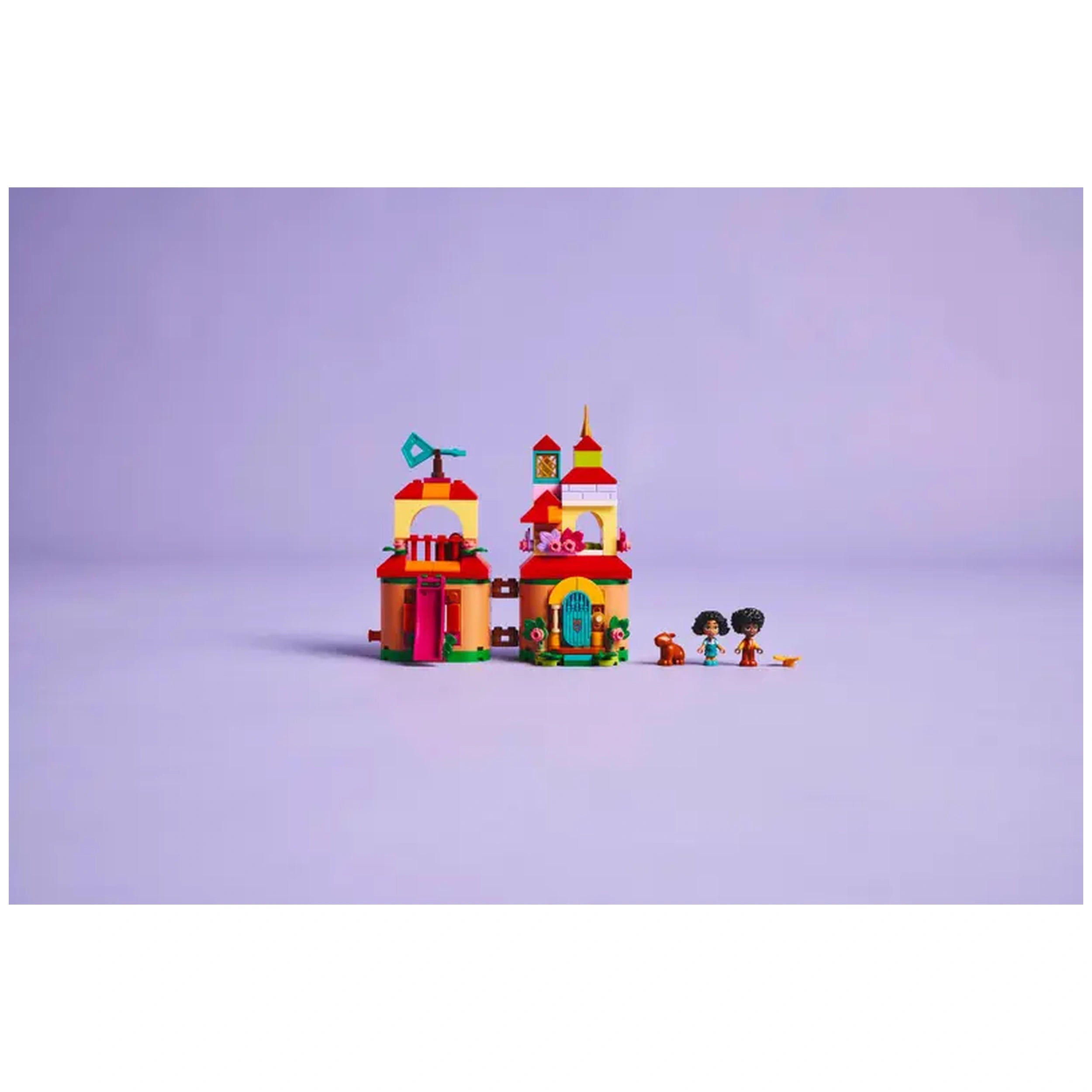 Colorful LEGO® Disney Encanto Mini House set features two vibrant buildings with red roofs, a green door, and a flag. Three characters, including Mirabel and a capybara, are positioned nearby on a soft purple background.
