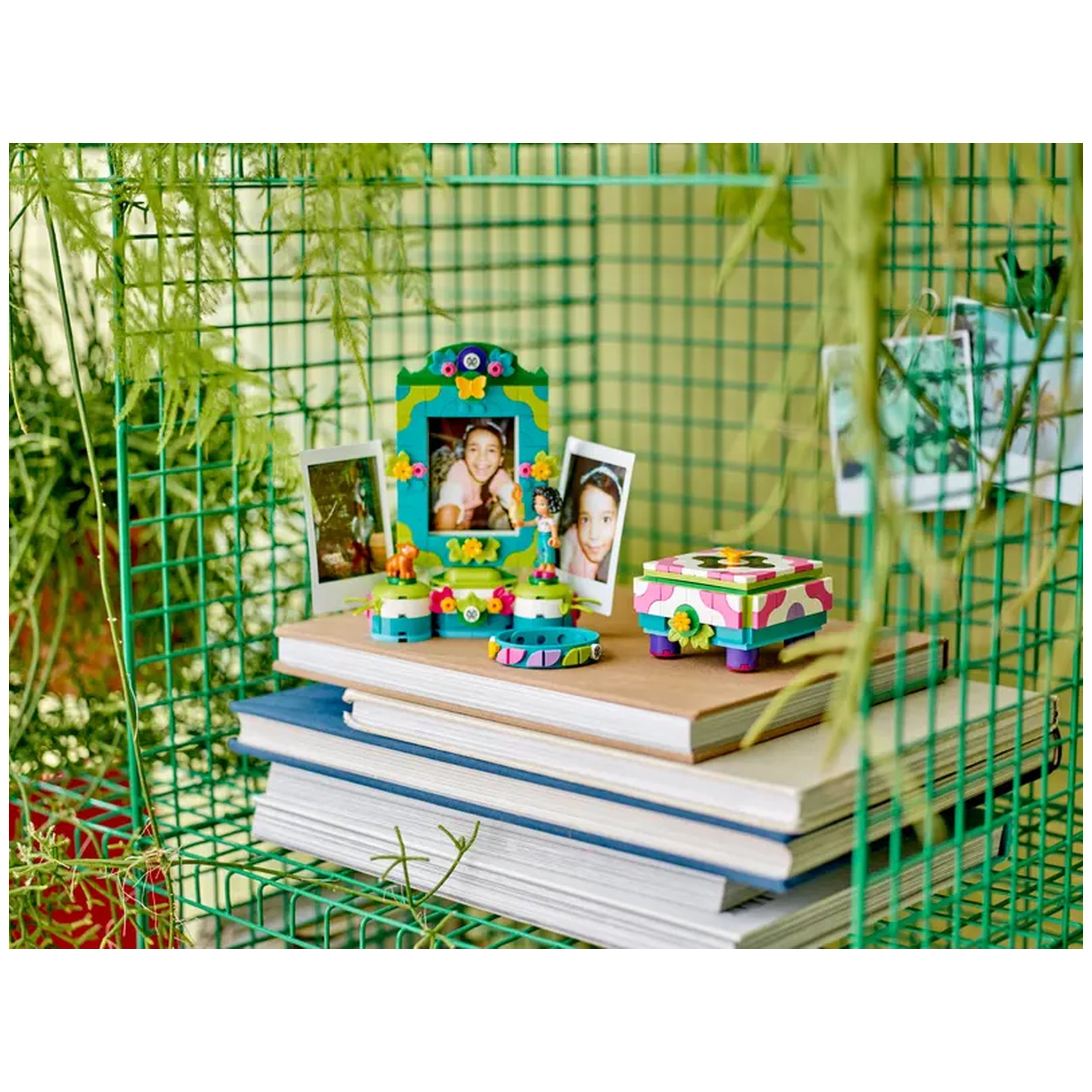 Colorful LEGO® Disney Encanto Mirabel-themed jewelry box and photo frame displayed on a shelf with books, featuring small photos and vibrant decorations.
