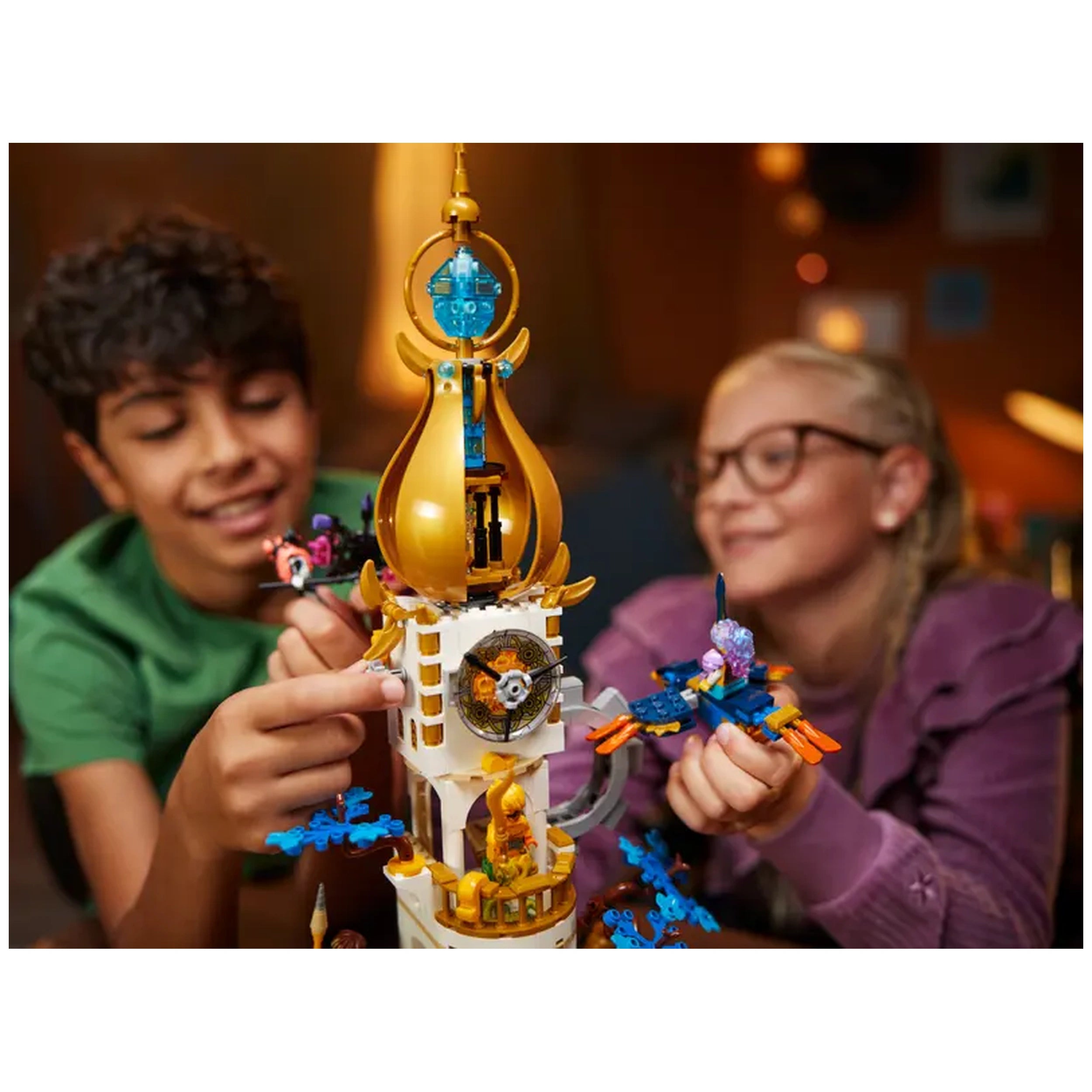 Two children play with the LEGO® DREAMZzz™ The Sandman's Tower, featuring a colorful tower and various engaged characters, in a cozy setting.